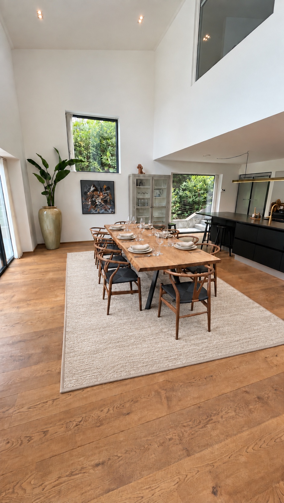 AI-edited photo of an oak dining table set for dinner, a pale wool rug and a black kitchen with garden views in a double-height private home